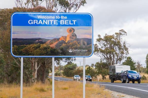 Un panneau de signalisation indiquant l’entrée de la région du Granite Belt et présentant un paysage pittoresque.