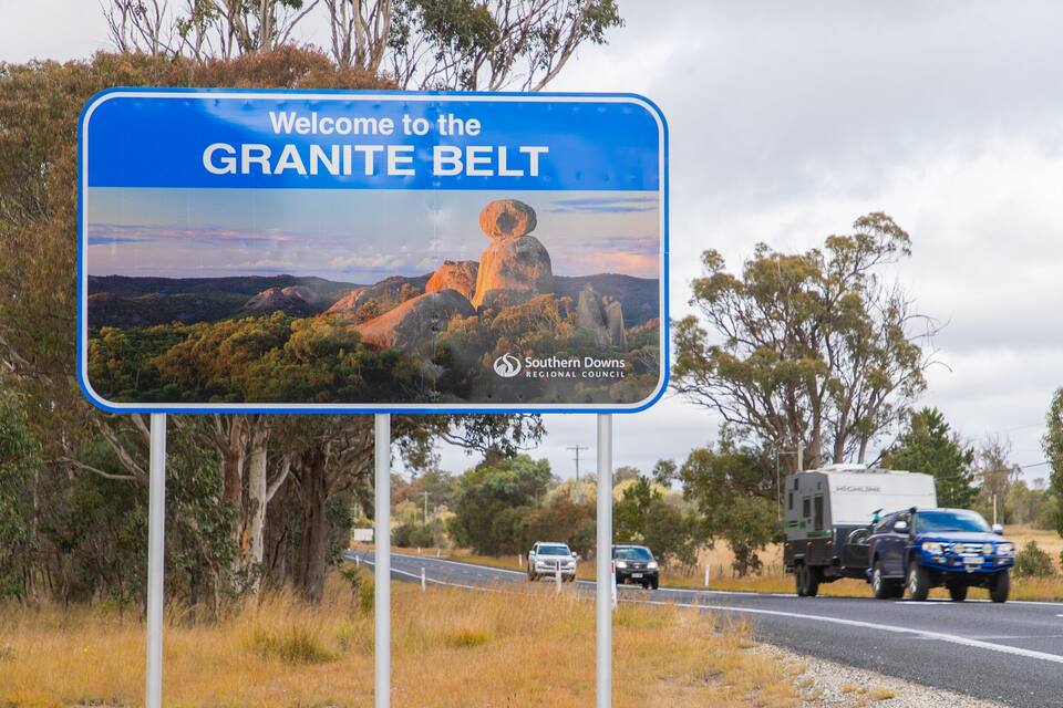 A road sign welcoming visitors to the Granite Belt with a scenic landscape.