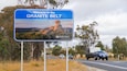 A road sign welcoming visitors to the Granite Belt with a scenic landscape.