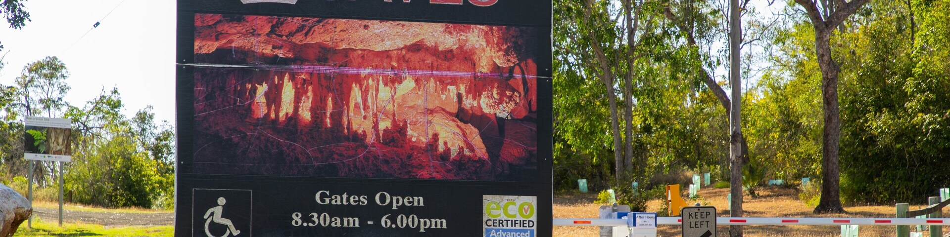 Un letrero da la bienvenida a visitantes en Capricorn Caves, con puertas abiertas desde las 8:30 de la mañana hasta las 6:00 de la tarde, y un aviso que dice 'No se admiten mascotas'.
