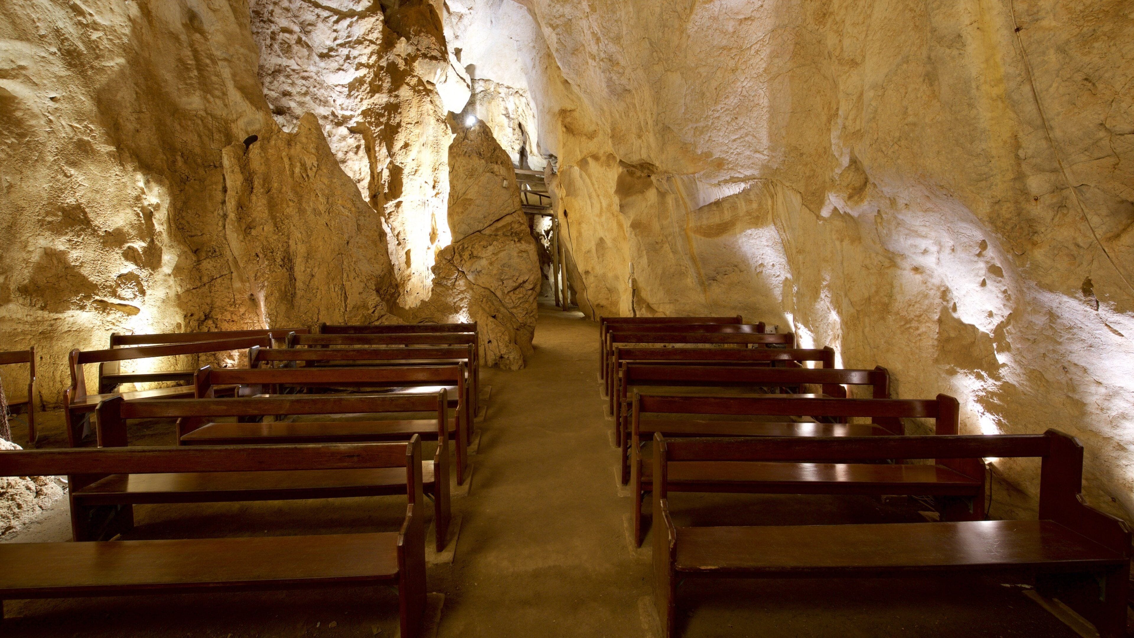 A cave interior with wooden benches arranged in rows.