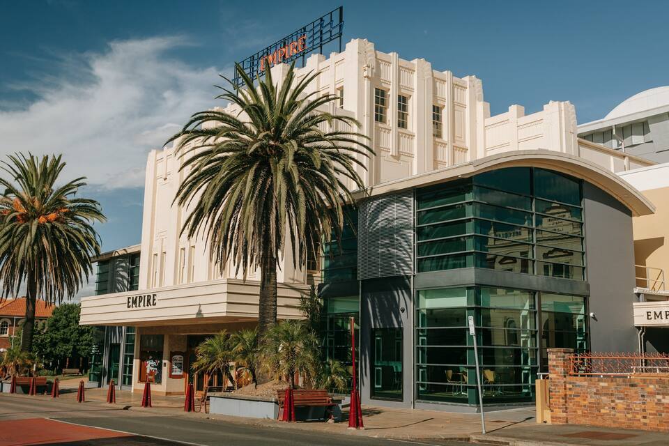 A building with a sign reading "EMPIRE" and palm trees in front.