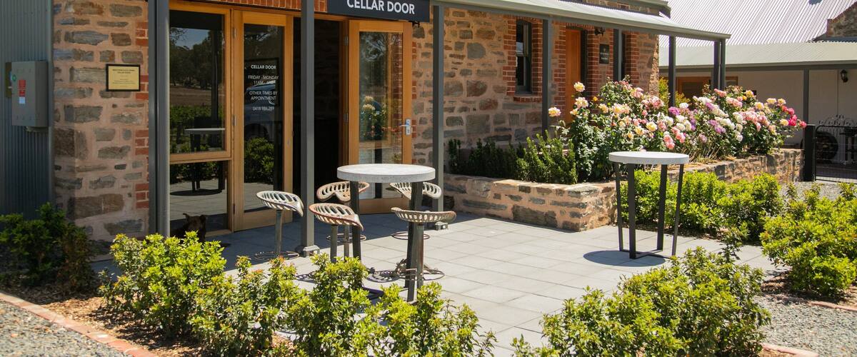 A stone building with a sign reading "Cellar Door" and outdoor seating.