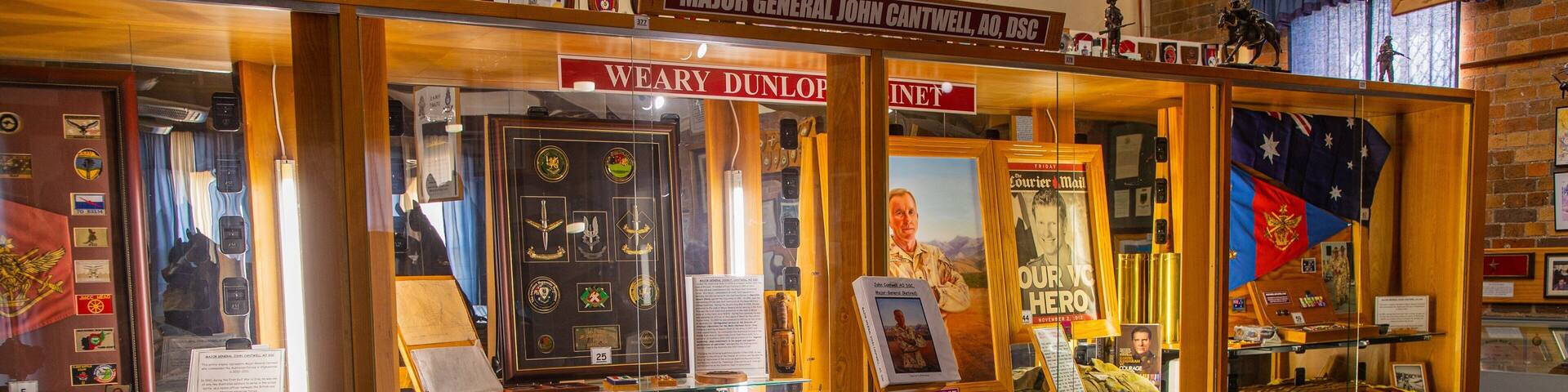 A military museum with displays of medals, framed documents, and portraits.