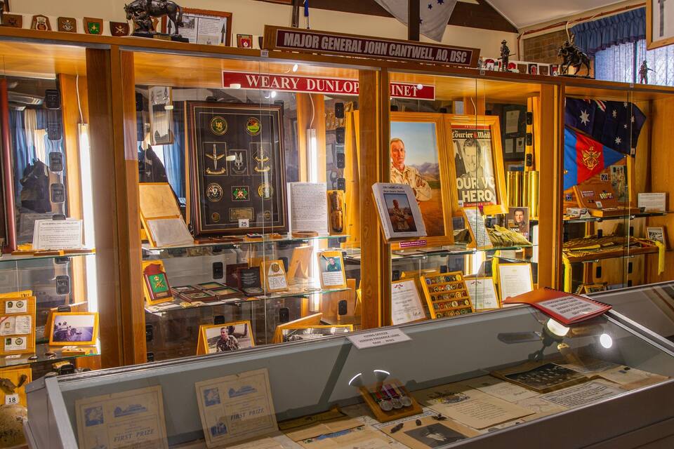 A military museum with displays of medals, framed documents, and portraits.