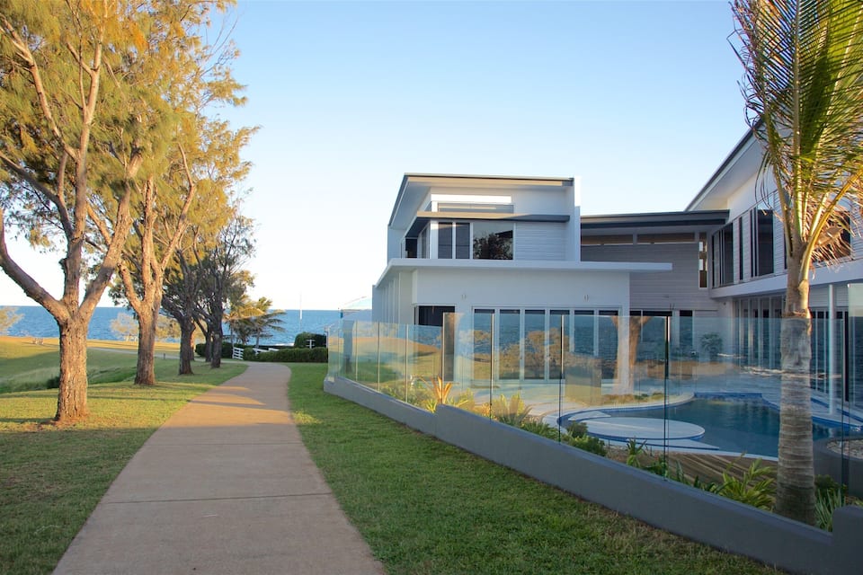 Una casa moderna con piscina e un vialetto alberato.