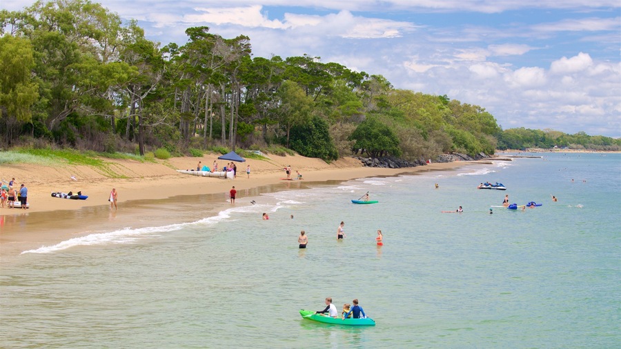 A beach with people swimming, paddling in boats, and sunbathing.
