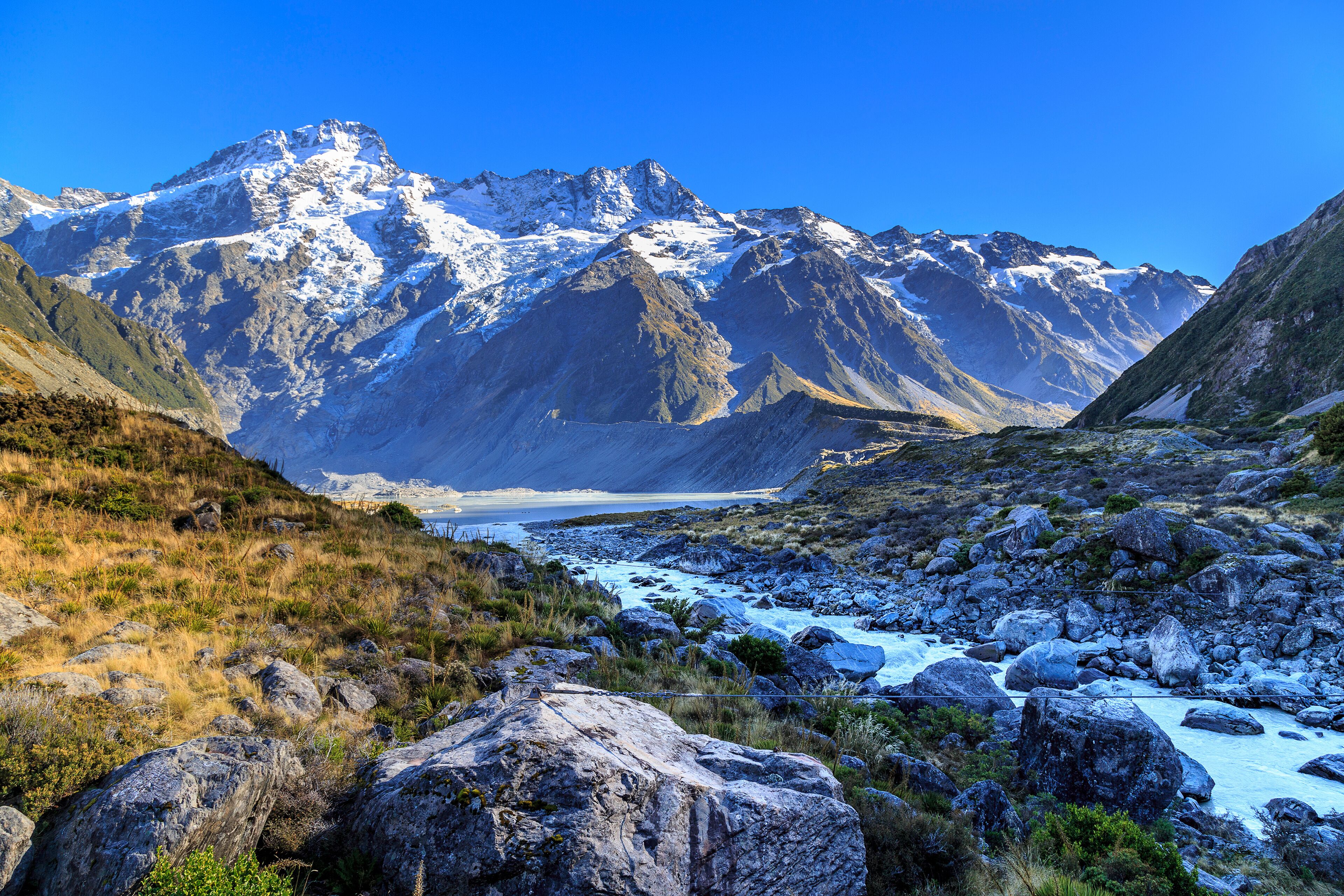 Aoraki/Mount Cook, Hooker Valley track with snowy mountain of Sefton mont, Mueller lake and river against blue sky, a must Hiking Trail destination in Queenstown, New Zealand