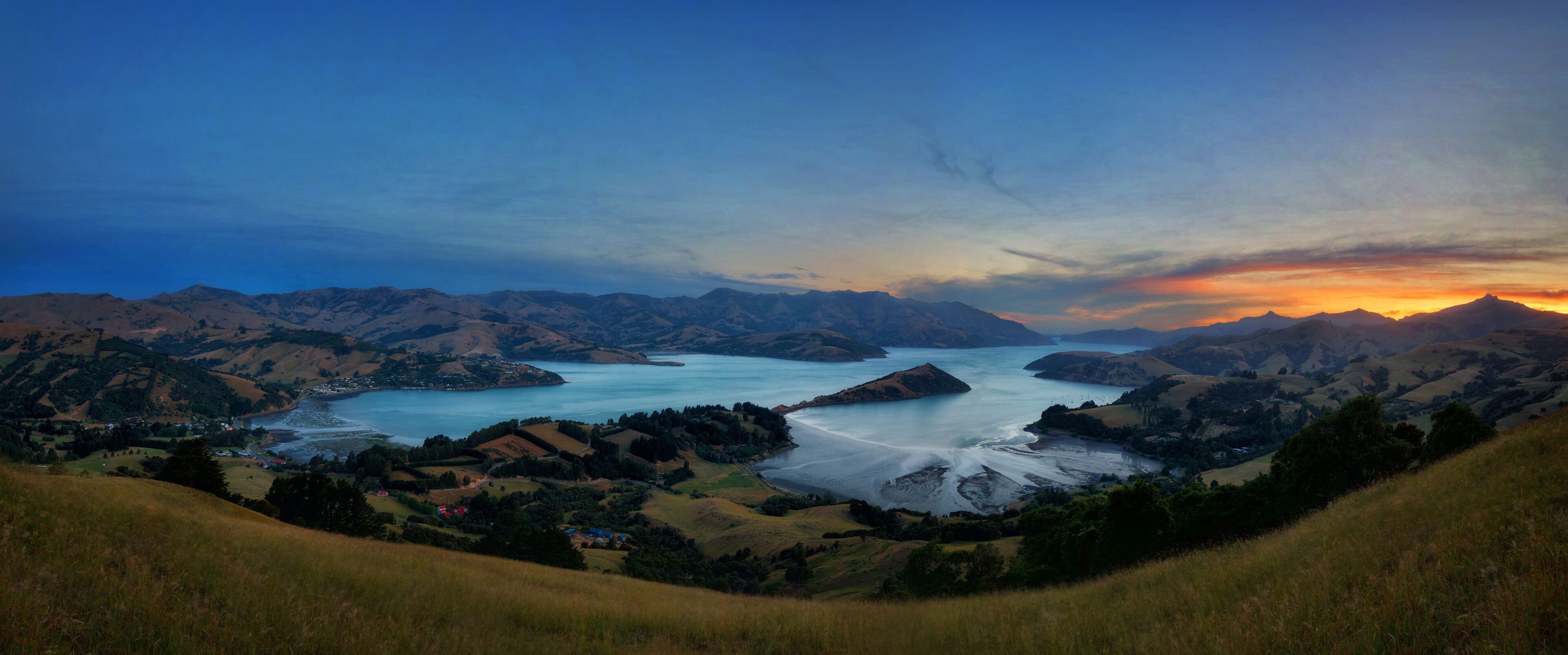 A coastal landscape with mountains, a bay, and a small settlement.