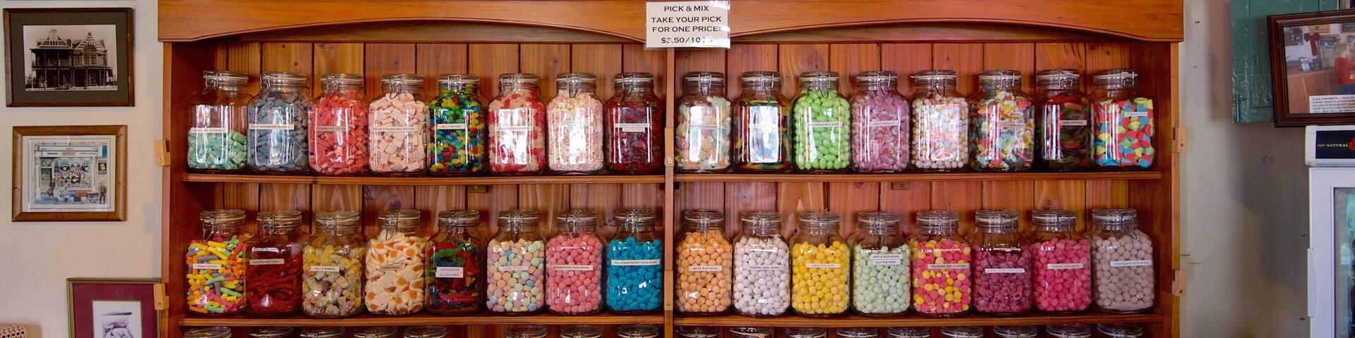Una tienda de dulces con frascos de caramelos variados en estantes.