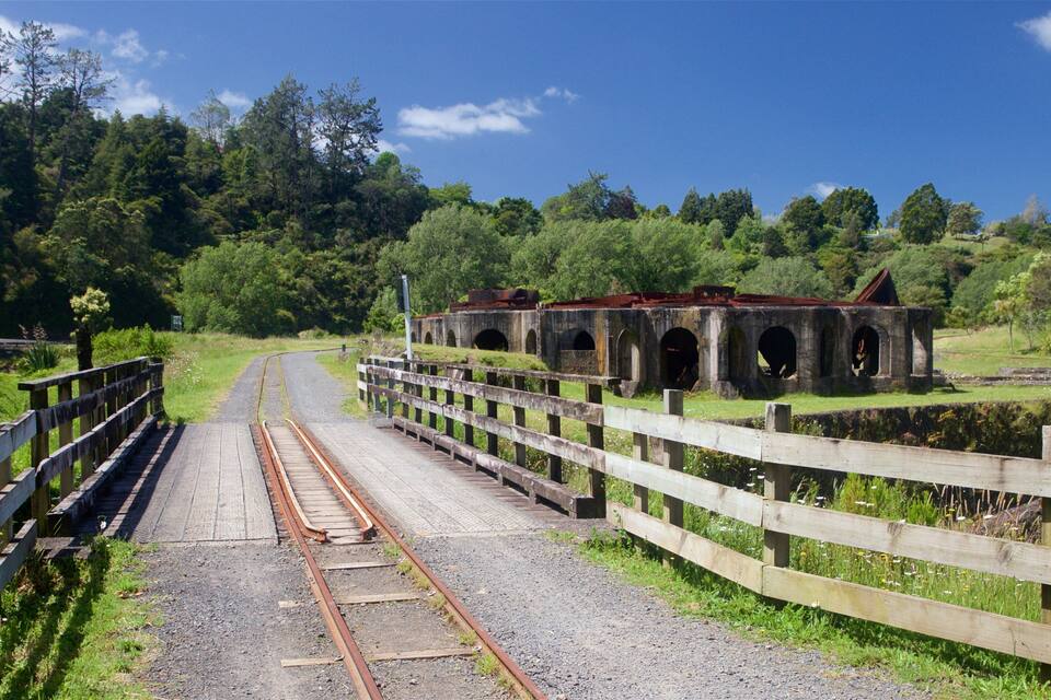 Eine Eisenbahnbrücke mit mehreren Bögen, umgeben von üppigem Grün und Bäumen.