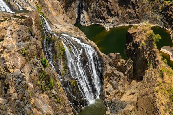 Ein mehrstufiger Wasserfall stürzt über steinige Klippen in eine Reihe von Becken.