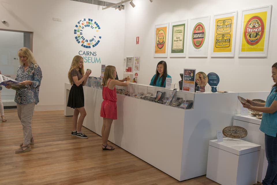 Exposição interior no Museu de Cairns, com diversos displays e cartazes informativos.