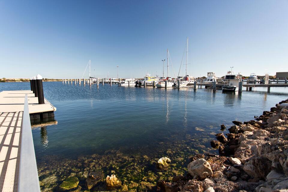 A marina with boats docked, clear water, and rocky shoreline.