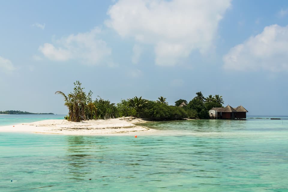 Uma ilha tropical com águas turquesa cristalinas, praias de areia branca e palafitas.