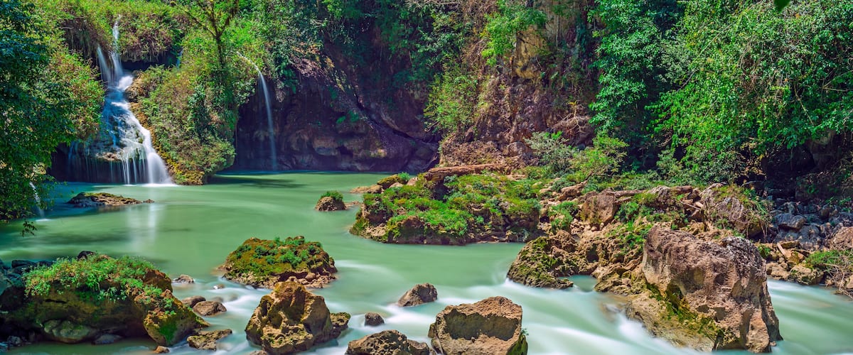 A waterfall, a river, and rocky terrain with greenery.
