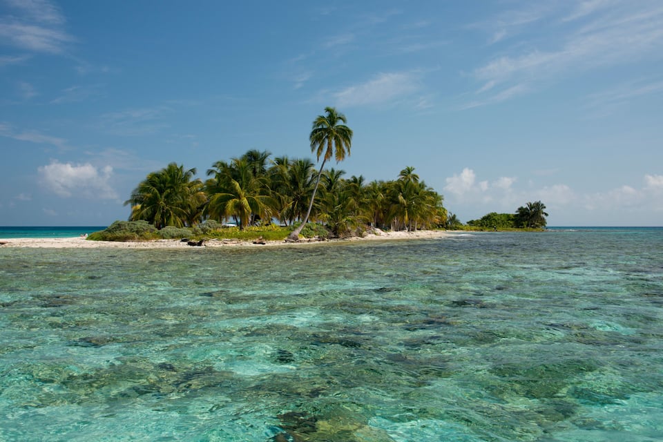 Una isla tropical con aguas turquesas cristalinas y palmeras.