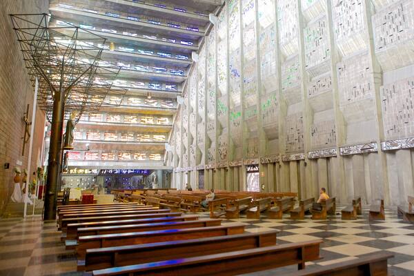 A large hall with wooden benches, a checkered floor, and walls covered with colorful text.