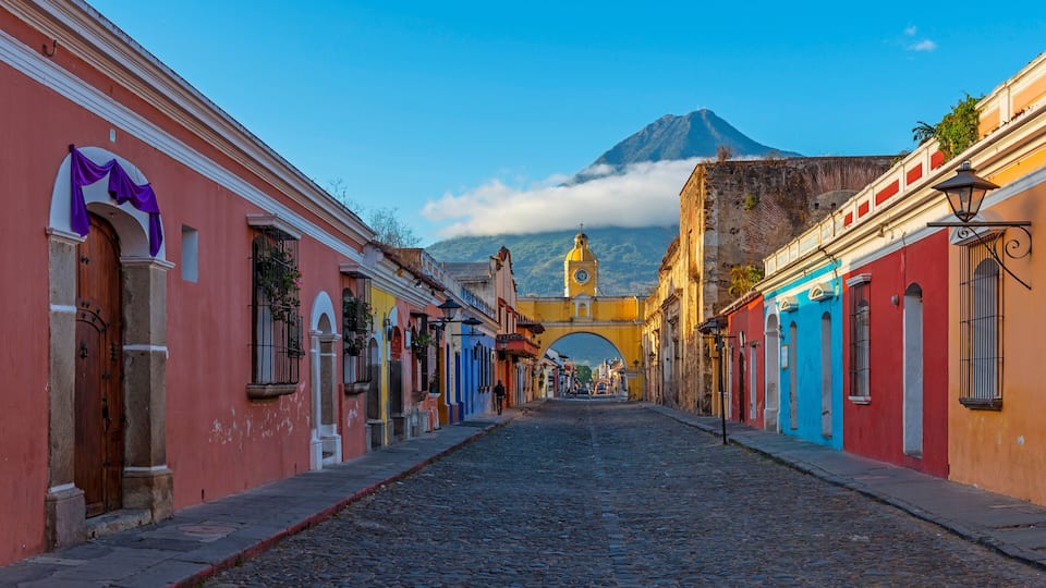 Cityscape of Antigua city at sunrise with Santa Catalina arch and Agua volcano, Guatemala.