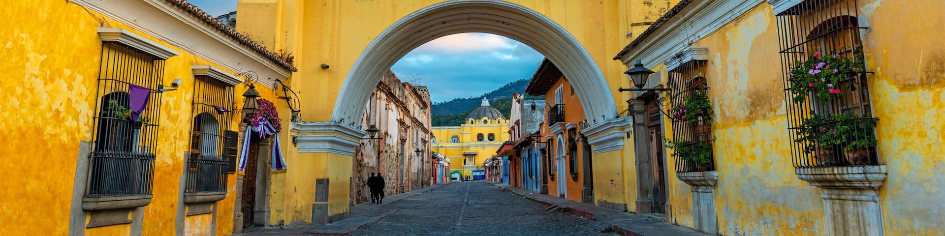 The Santa Catalina arch and the main street of Antigua city at sunrise, Guatemala.