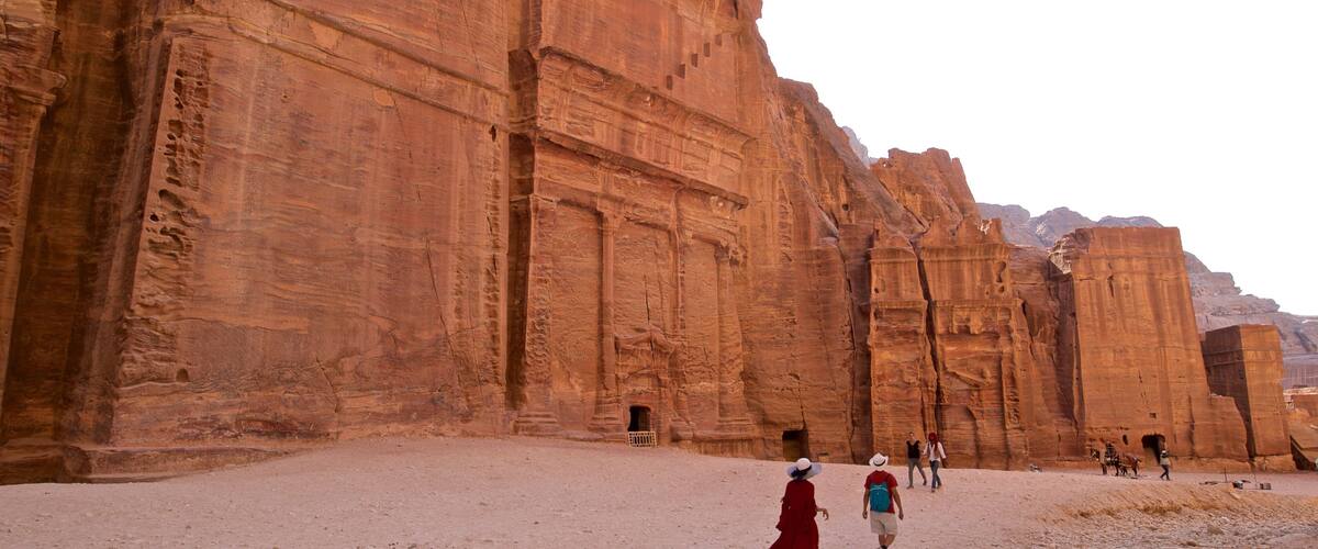 Street of Facades featuring a gorge or canyon and heritage architecture as well as a small group of people