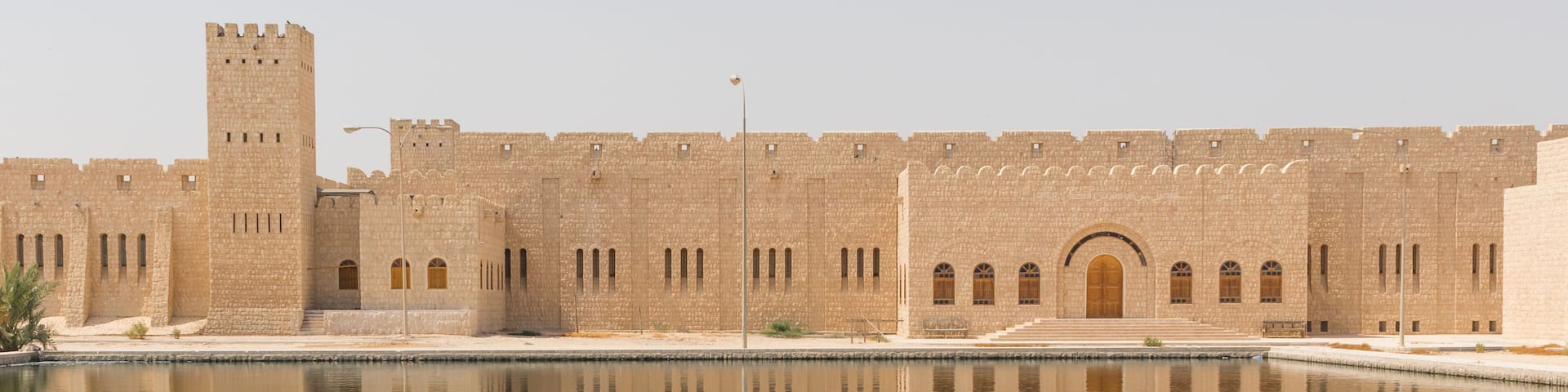 A large fortress with a central tower and a moat in front.
