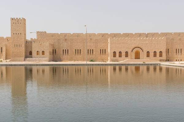 A large fortress with a central tower and a moat in front.