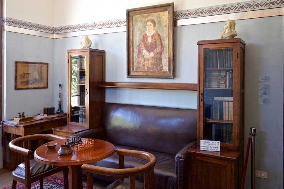 A room with a chessboard, bookshelves, a couch, and a painting.