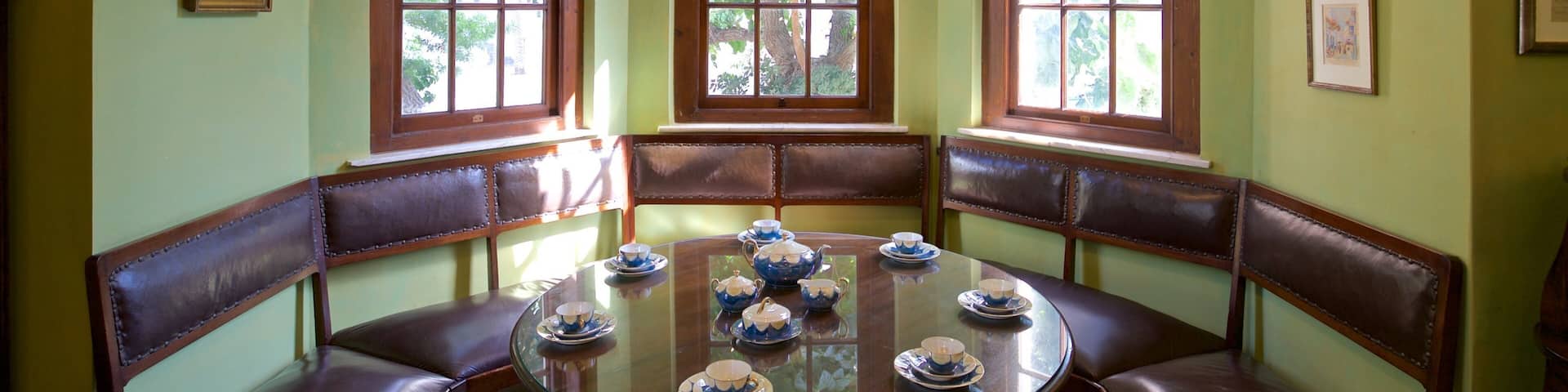 Un comedor con una mesa redonda de vidrio, sillas de cuero marrón y un ventanal de varios paneles.