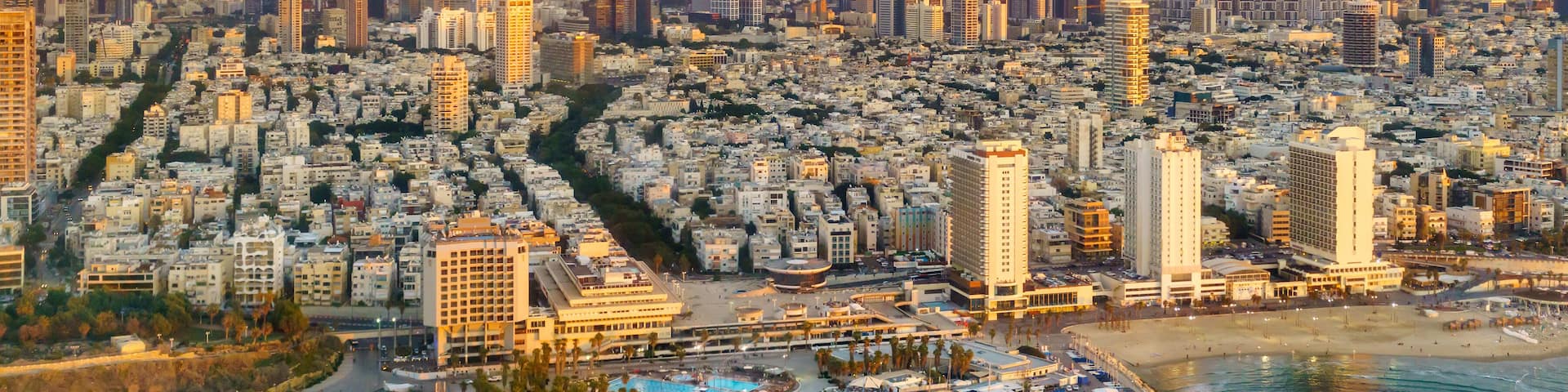 A coastal cityscape with a marina, high-rise buildings, and a clear sky.