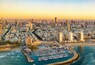 Un paysage urbain côtier avec un port de plaisance, des immeubles de grande hauteur et un ciel dégagé.