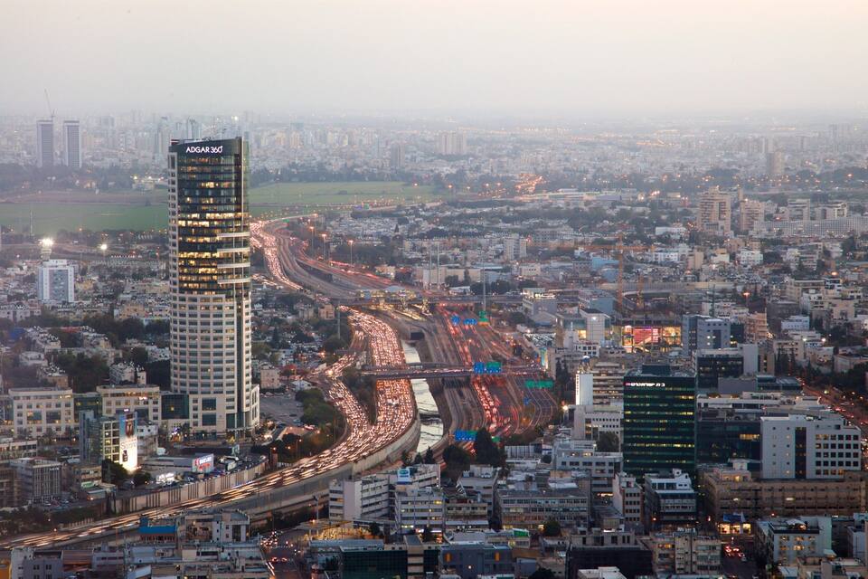 A cityscape with a prominent ADGAR 360 building, busy highways, and dense urban architecture.