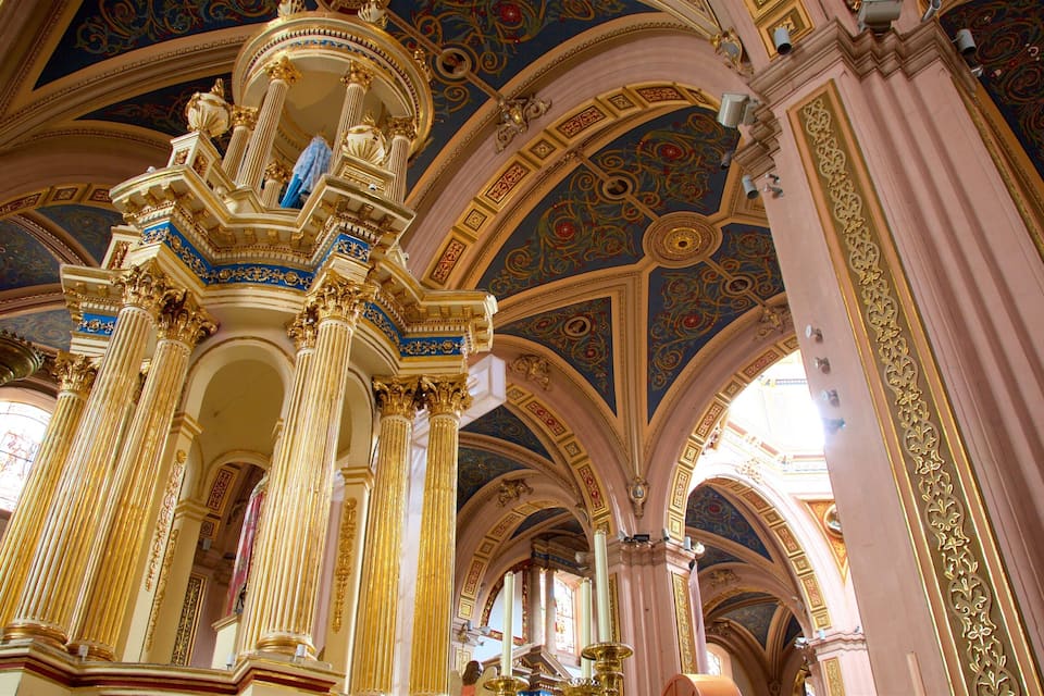 Un intérieur somptueux, avec des colonnes dorées, des motifs complexes au plafond et des murs roses.