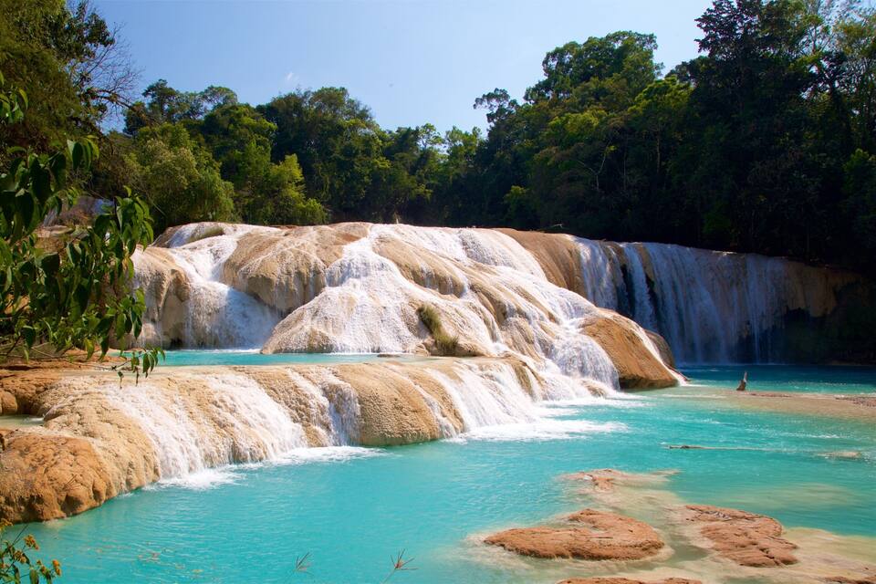 A turquoise pool surrounded by terraced limestone formations with cascading waterfalls.