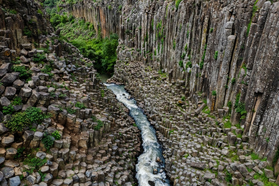 Un río serpentea por un cañón de paredes rocosas y vegetación.