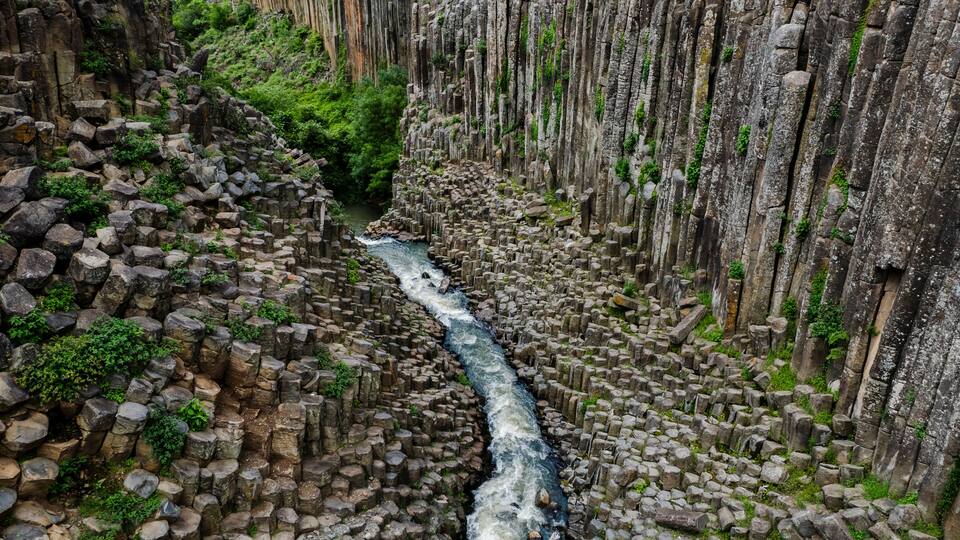 A river flowing through a canyon with rocky walls and greenery.