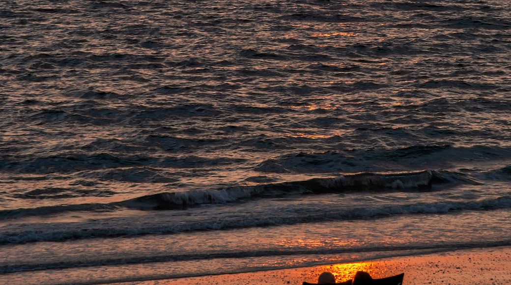 A silhouetted couple in chairs watch the sunset along Bonita Beach in Bonita Springs, Florida.