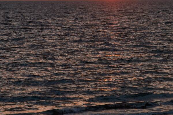 A silhouetted couple in chairs watch the sunset along Bonita Beach in Bonita Springs, Florida.