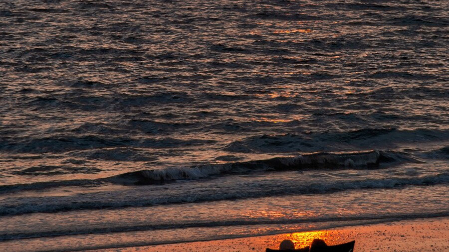 A silhouetted couple in chairs watch the sunset along Bonita Beach in Bonita Springs, Florida.