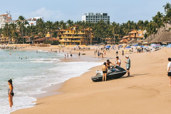 Una playa con gente, un jet ski y palmeras.