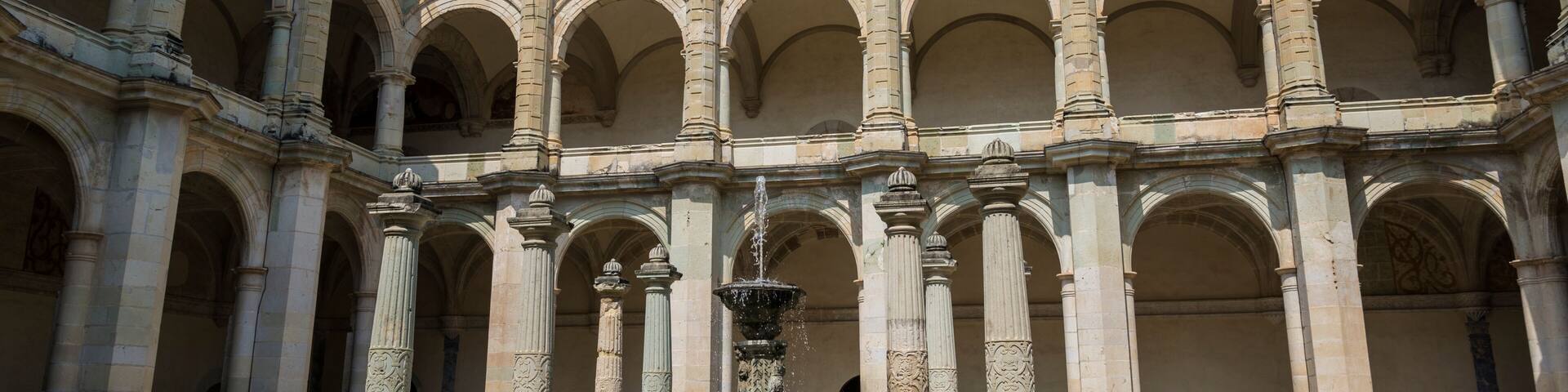 A historic courtyard with a fountain, arches, and a dome structure.