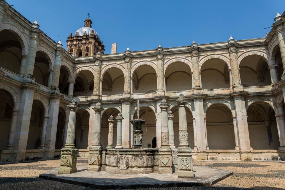 Ein historischer Innenhof mit Brunnen, Bögen und einer Kuppelkonstruktion.