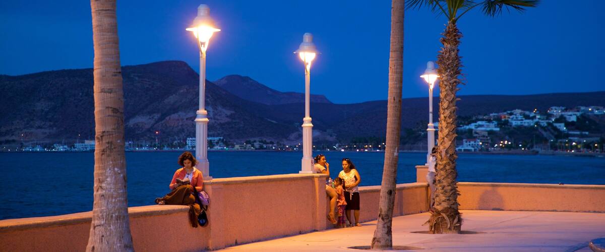 Malecon Kiosk which includes general coastal views and night scenes as well as a small group of people