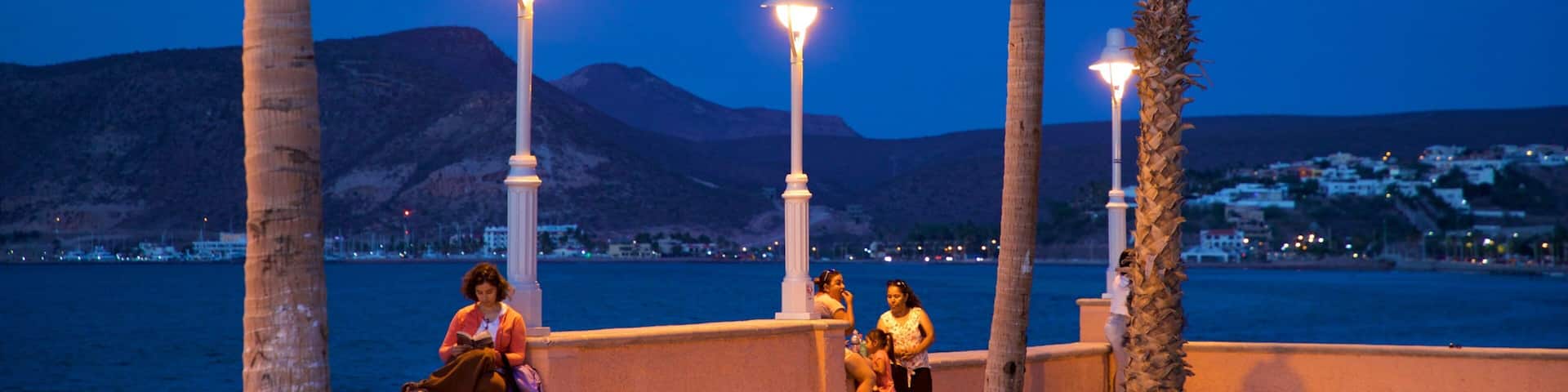 Malecon Kiosk which includes general coastal views and night scenes as well as a small group of people