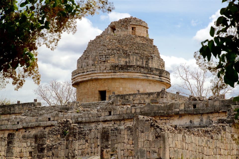 A historical stone structure with a dome and surrounding walls, surrounded by trees.