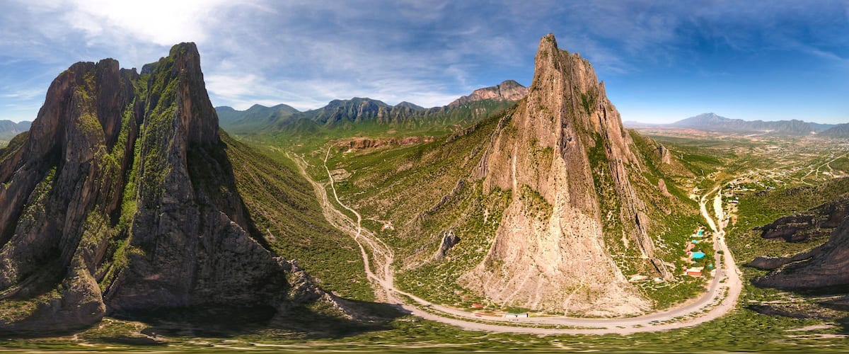 A mountainous landscape with prominent rock formations and a winding road.