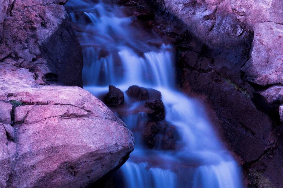 Una cascada que fluye por un desfiladero rocoso con grandes rocas.