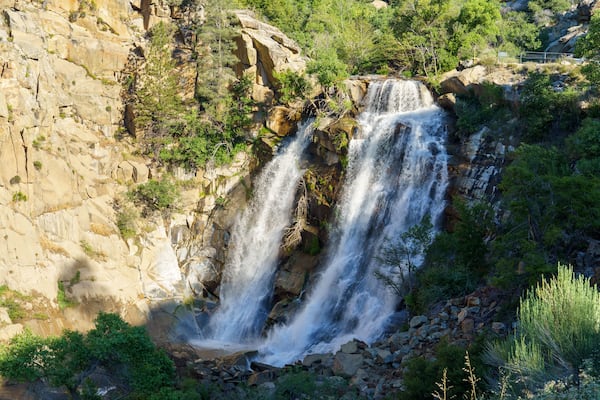 Une cascade se déversant le long d’une falaise rocheuse, entourée d’une végétation luxuriante.