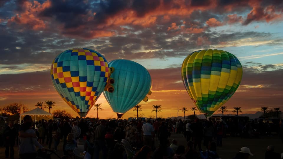 Tres coloridos globos aerostáticos contra un cielo al atardecer.