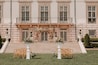 Elegant outdoor wedding setup with floral arch in front of a mansion